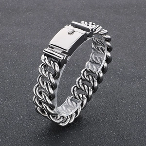 Detail of silver stainless steel Cuban link bracelet with square safety clasp on black surface