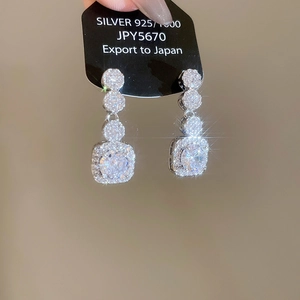 Macro shot of S925 silver earrings with sparkling zircon geometric drop and square stones