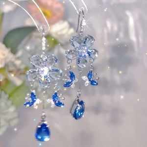 Detail of silver floral earrings with blue crystal butterflies and water drop tassels