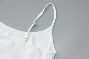 Detailed macro view of white slim fit dress showing adjustable silver metal strap buckles