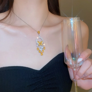 Detail of silver necklace with yellow and white butterfly drop tassels on a model