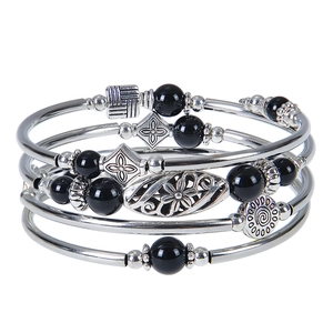 Detail of bohemian multilayer stretch bracelet with black beads and silver metal charms