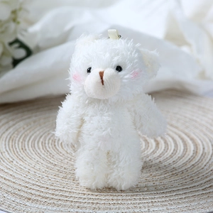 Close-up of white plush teddy bear charm with pink blush cheeks and a hanging loop