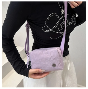 Dettaglio della borsa a tracolla in nylon lavanda con cinturino regolabile e logo