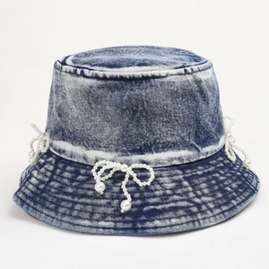 Detail of blue denim bucket hat featuring elegant pearl bow decoration and vintage wash
