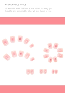 Detailed flat lay of pink gradient press-on nails with red heart patterns and white accents