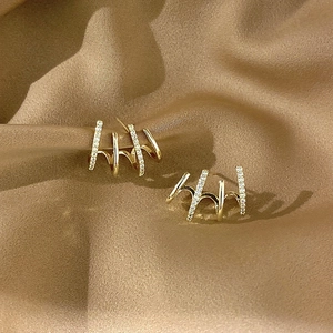 Detail view of gold earrings with cubic zirconia on brown pleated silk background