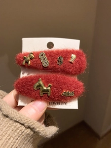 Detail of red plush hair clips featuring golden horse pendants and handmade metal charms