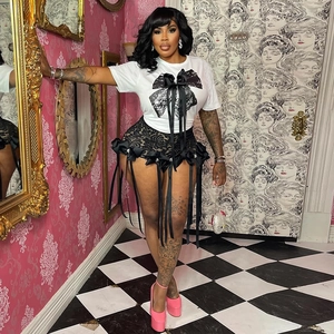 Détail d'un t-shirt blanc avec nœud papillon et short en dentelle avec rubans suspendus