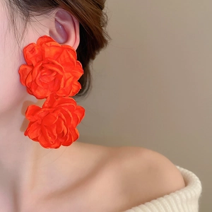 Close-up of double-layered orange fabric rose earrings on a model with elegant texture
