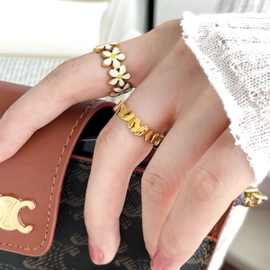 Cute gold daisy enamel and hollow heart rings worn by a model in a stylish setting