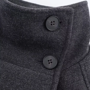 Detailed macro shot of dark grey wool coat lapel with black buttons and fine stitching