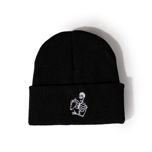 Détail d'un bonnet noir avec broderie d'un squelette buvant du café, style tendance