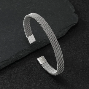 Minimalist silver steel mesh stretch bracelet on a dark textured slate background