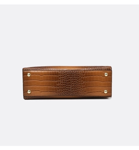 Detailed bottom view of brown croc-pattern leather bag featuring gold protective metal feet