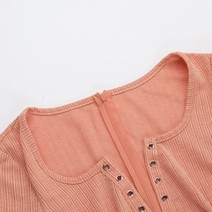 Dettaglio dell'abito in maglia a coste arancione con scollo a V, zip e occhielli in metallo