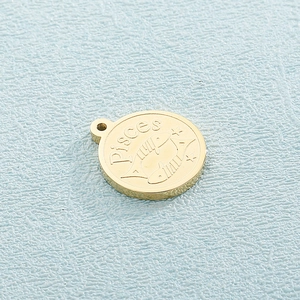 Macro shot of golden Pisces zodiac charm with engraved fish symbol on blue background