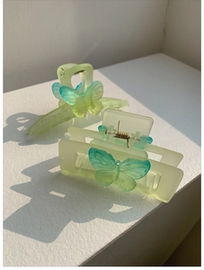 Detail of two matte gradient butterfly hair claws in soft green and cyan shades