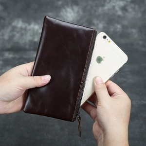 Inserting smartphone into dark brown leather pouch to show capacity and crazy horse texture