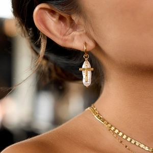Detail of baroque pearl earring with golden cross inlay and smooth circular hoop clasp