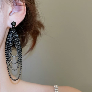 Vue macro de côté de longues boucles d'oreilles noires à pampilles en strass sur un mannequin