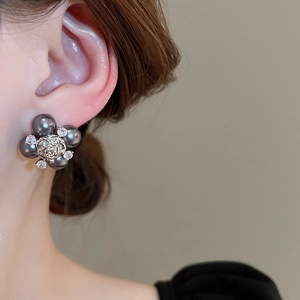 Gros plan sur des boucles d'oreilles vintage avec perles grises et rose argentée