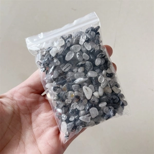 Close-up of a hand holding a bag of natural black rutilated quartz crystal stones