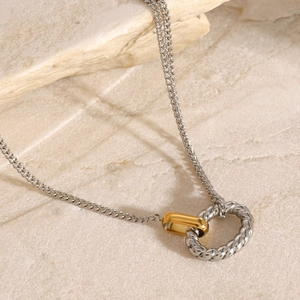 Macro detail of interlocking gold smooth ring and silver twisted rope ring pendant
