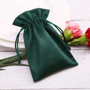 Deep green velvet drawstring pouch for jewelry gift storage on a white background
