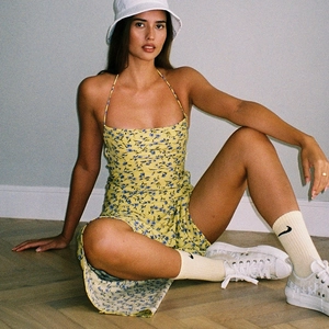 Detail of yellow floral summer dress with side slit and backless halter neck design