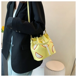 Detail of yellow lemon-shaped bucket bag with drawstring and fruit slice decoration