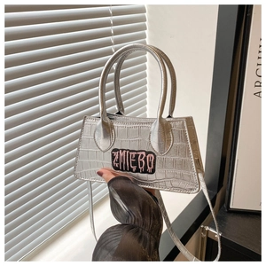 Detailed macro view of silver crocodile textured PU leather bag with pink letter embroidery