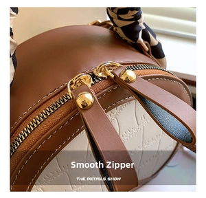 Detail of smooth gold double zippers on brown croc-embossed bag with silk scarf handle
