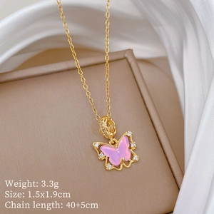 Détail d'un pendentif papillon rose avec cristaux sur une chaîne dorée dans un coffret