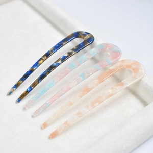 Three acetate U-shaped hair pins with tortoiseshell patterns in blue, pink, and beige colors