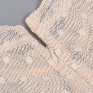 Detail of invisible zipper and apricot polka dot mesh fabric on the puff sleeve dress