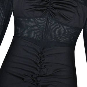 Close-up of black bodycon dress featuring elegant ruching details and sheer mesh waist panel
