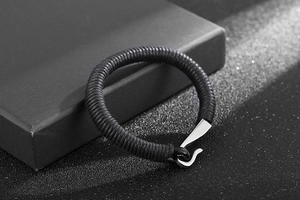 Detail of black braided leather bracelet with silver hook clasp on a gift box