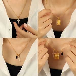 Gold layered necklace with cross pendant, sunburst plaque, and black zircon stone