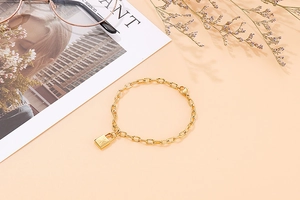 Close-up of golden chain bracelet with padlock pendant featuring sunray engraving detail