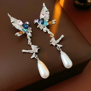 Détail de boucles d'oreilles oiseau vintage avec cristaux colorés et perles pendantes