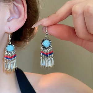 Detail of bohemian tassel earrings with turquoise stones and red and blue beads