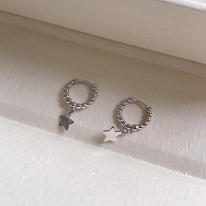 Macro detail of S925 sterling silver hoop earrings with bead texture and star charms