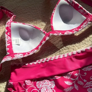 Dettaglio bikini floreale rosa con bordi smerlati ed etichetta di lavaggio taglia S
