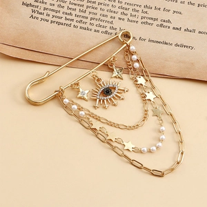 Detail of vintage gold evil eye brooch with pearl tassel chains and rhinestone stars