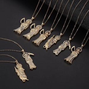 Gros plan de pendentifs Santa Muerte dorés avec zircons sur fond texturé noir
