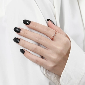 Close-up of a rose gold wave ring with zircon pave, worn on a hand with black nail polish