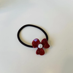 Detailed shot of red jelly petal hair tie with a white pearl center on black elastic band