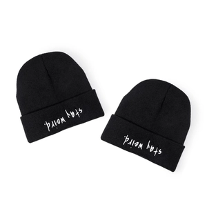 Minimalist black knitted beanie featuring inverted 'stay weird' embroidery on folded cuff
