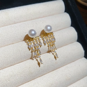 Macro detail of 14K gold plated long tassel earrings with pearls and marquise cut zircons